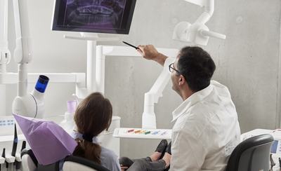 Odontólogo revisando una radiografía dental junto a la paciente en el gabinete