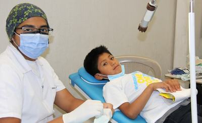Odontopediatra atendiendo a un niño sentado en el sillón dental