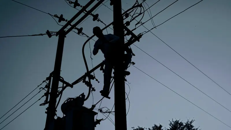 Electricista trabajando en líneas eléctricas al atardecer