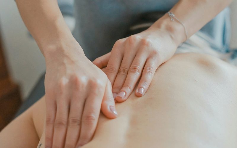 Manos de una profesional aplicando un masaje corporal sobre la espalda de una clienta