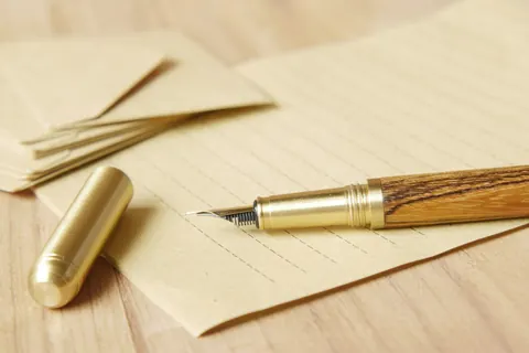 Pluma estilográfica sobre un documento y sobres de papel en una mesa