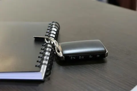 Llave de coche junto a un cuaderno de espiral sobre una mesa oscura