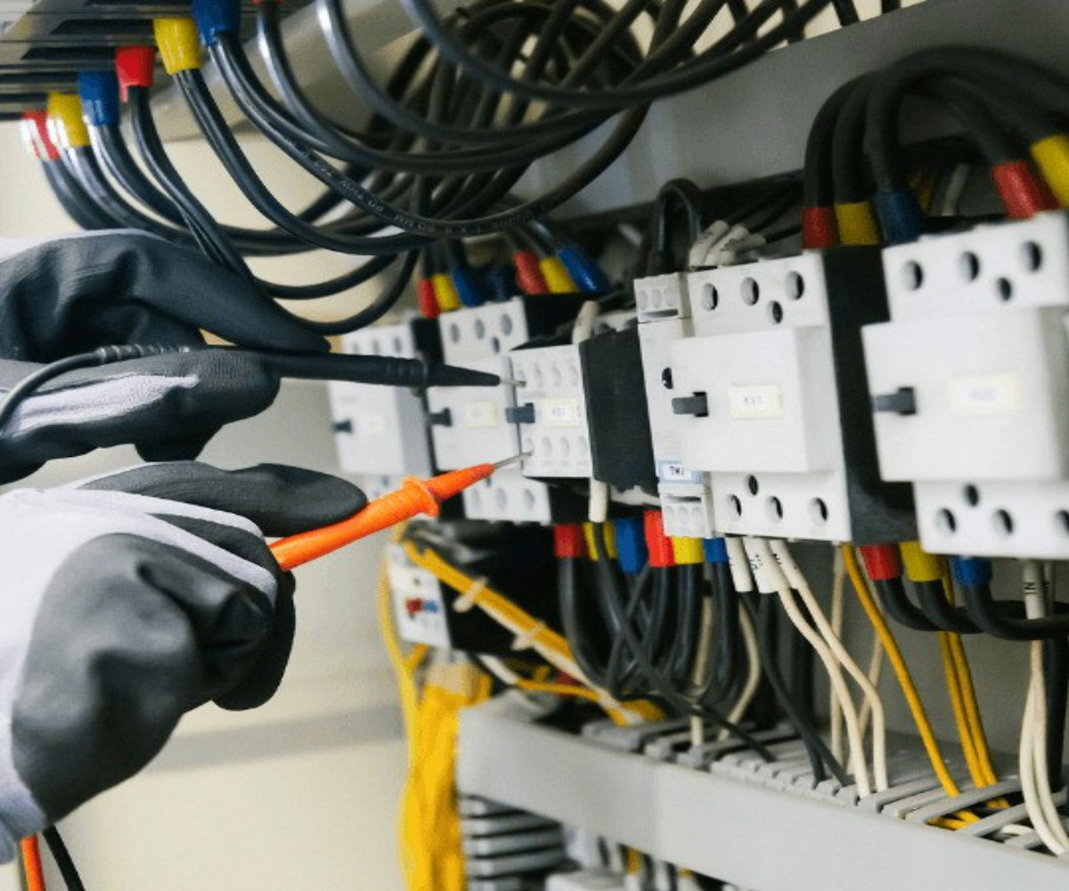 Electricista con guantes comprobando un cuadro eléctrico con un multímetro