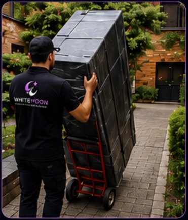 Operario de WhiteMoon transportando cajas apiladas con una carretilla