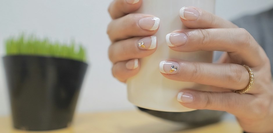 Manos con manicura francesa sujetando una taza blanca