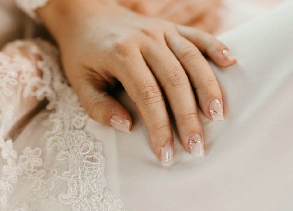 Mano con manicura francesa apoyada sobre encaje blanco