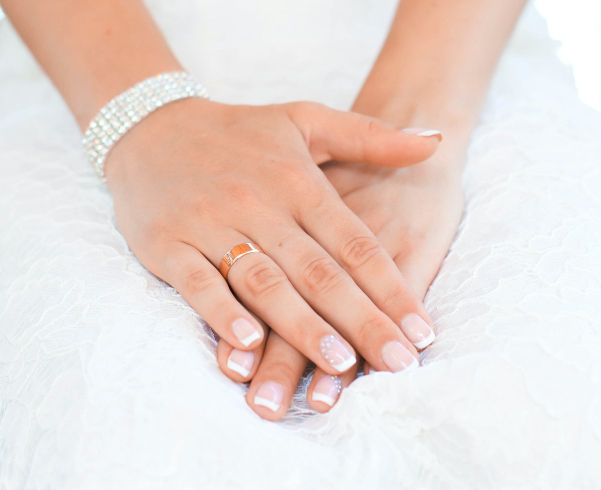Manos cruzadas con uñas en degradado de rosa a blanco, estilo baby boomer