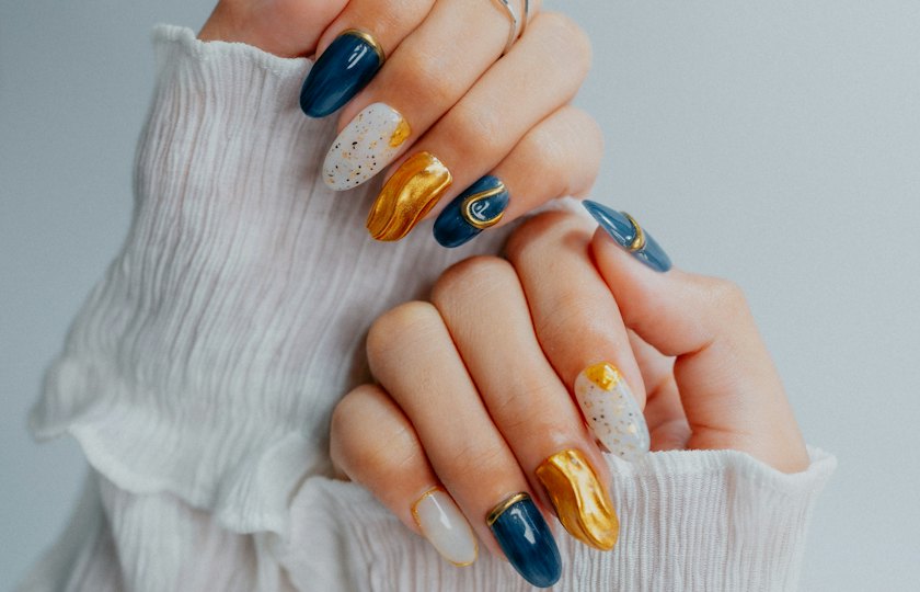 Manos con nail art en azul marino, dorado y blanco