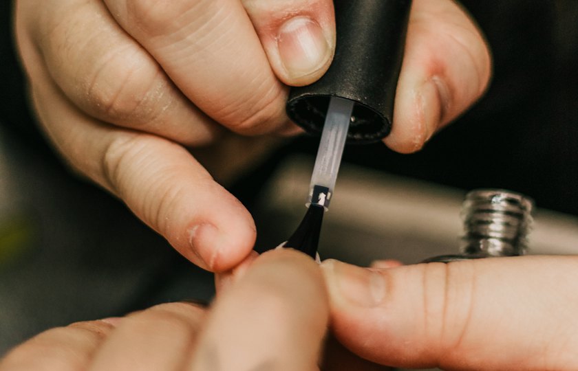 Pincel aplicando esmalte sobre una uña