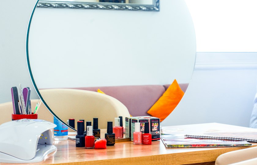 Mesa de manicura con lámpara, esmaltes y un espejo redondo