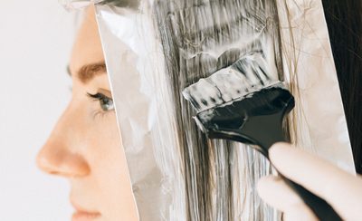 Aplicación de mechas con papel de aluminio y brocha sobre el pelo de una clienta