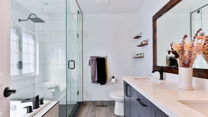 Baño reformado con ducha de obra, mampara de cristal y mueble con doble lavabo