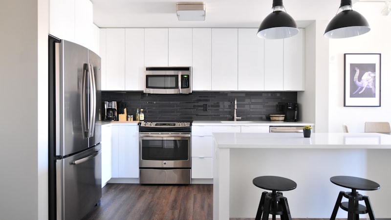 Cocina reformada con muebles blancos, isla y electrodomésticos de acero inoxidable