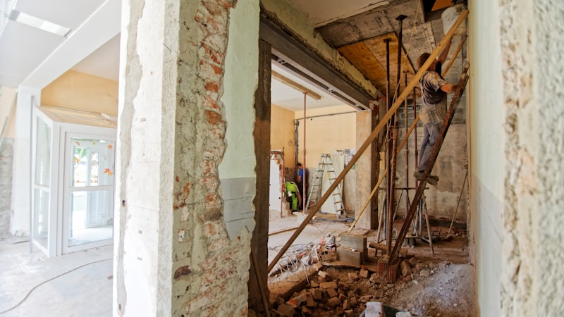 Vivienda en obra con tabiques abiertos y un operario trabajando sobre un andamio