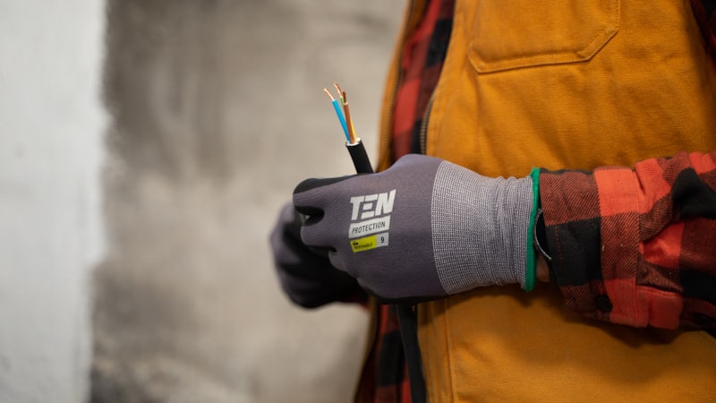 Operario sujetando un cable eléctrico pelado con guantes de protección