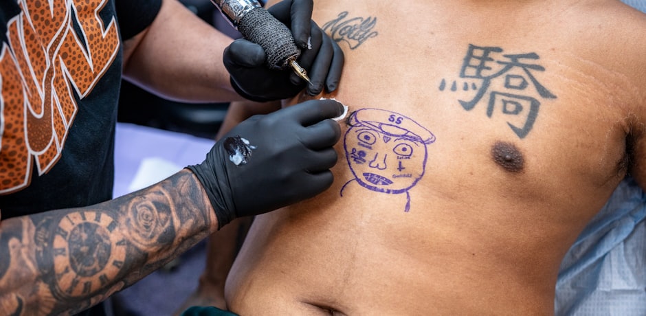 Tatuador tatuando un diseño dibujado en el pecho de un cliente