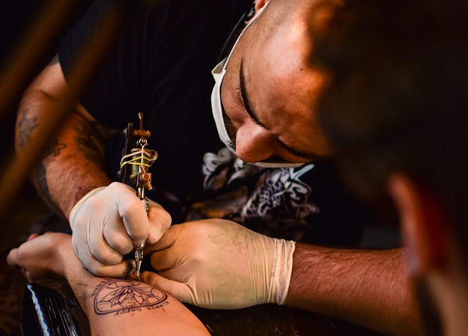 Tatuador con mascarilla trabajando de cerca sobre la piel