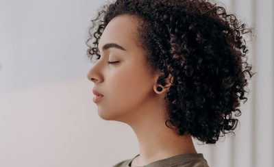 Persona con los ojos cerrados y las manos juntas durante una sesión de meditación