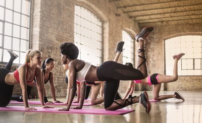 Clase de pilates de suelo trabajando sobre esterillas en cuadrupedia
