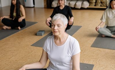 Personas sentadas sobre esterillas con los ojos cerrados en una clase de ritmo lento
